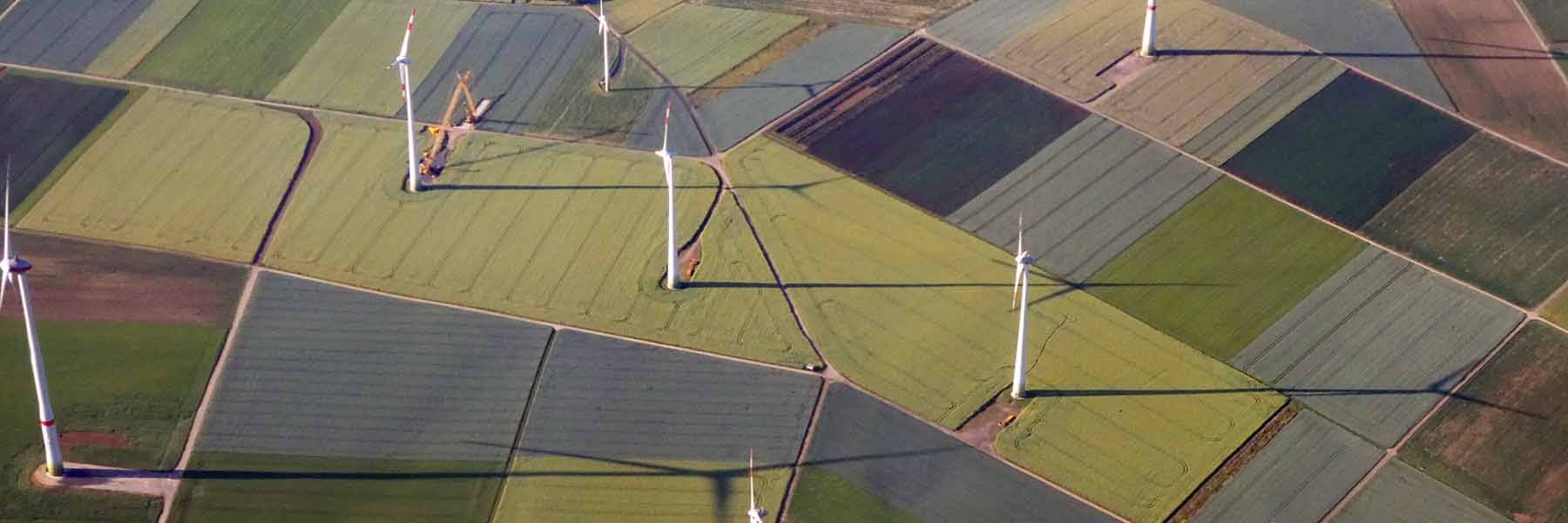 Wind turbines sit on gridded farmland. Photo by Mark König on Unsplash.