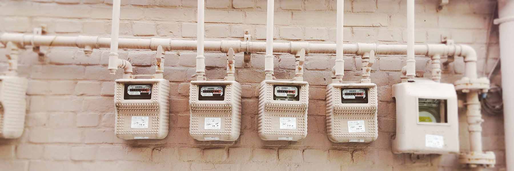 A line of building utility meters painted a light tan. Photo by Linh Ha on Unsplash.
